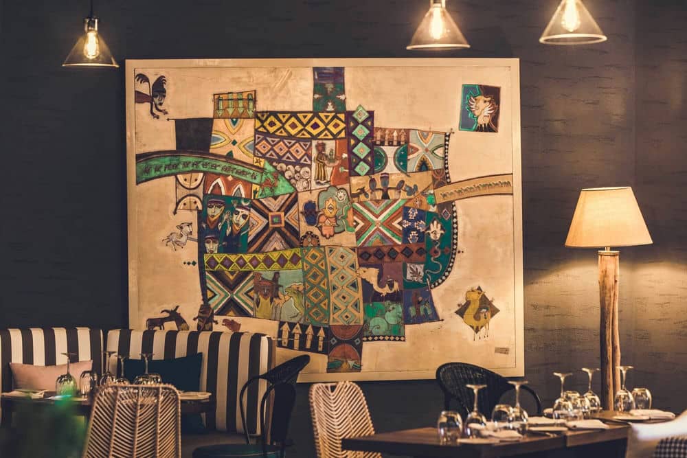 http://Intérieur%20d’un%20restaurant%20chic%20avec%20œuvre%20artistique%20murale%20colorée%20et%20ambiance%20chaleureuse.