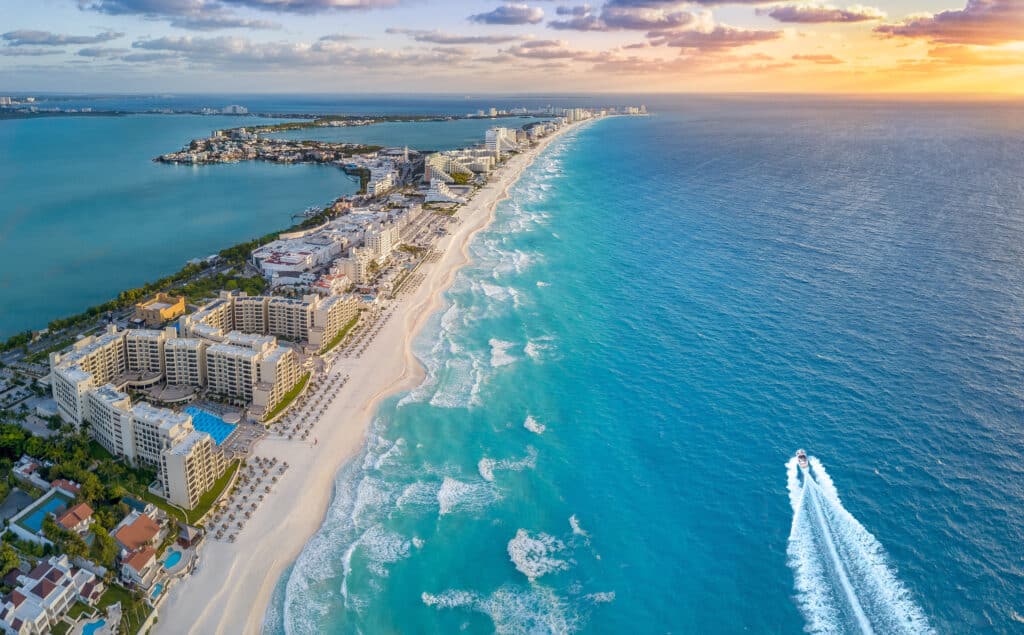 Vue aérienne de la plage de Cancún et de la zone hôtelière bordée de palmiers.