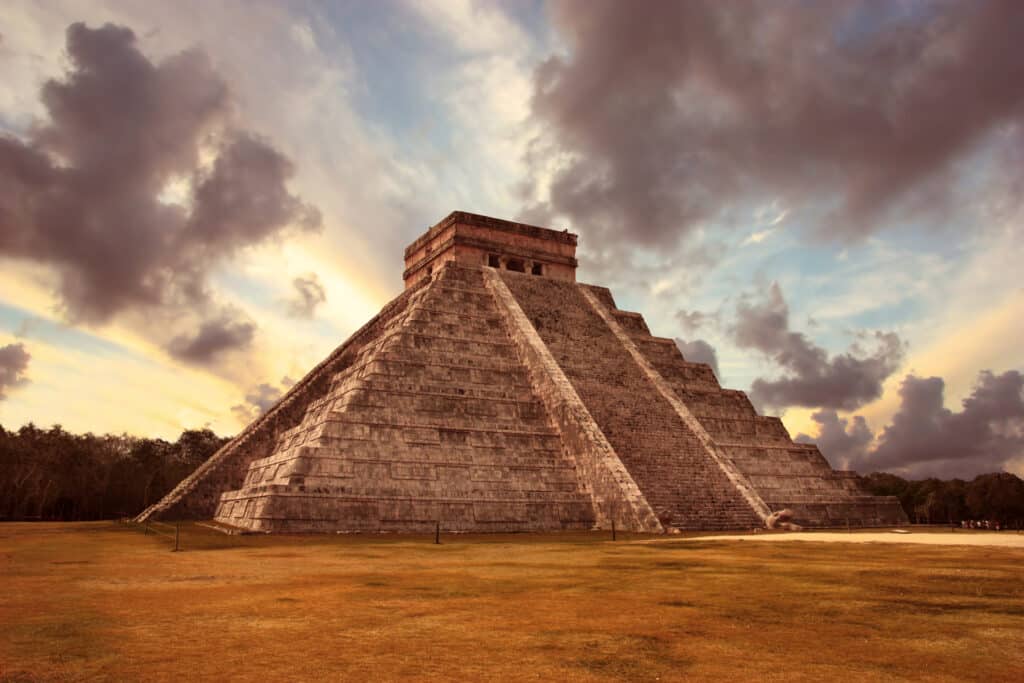 Pyramide de Chichen Itza sous un ciel nuageux au coucher du soleil, site maya emblématique au Mexique.