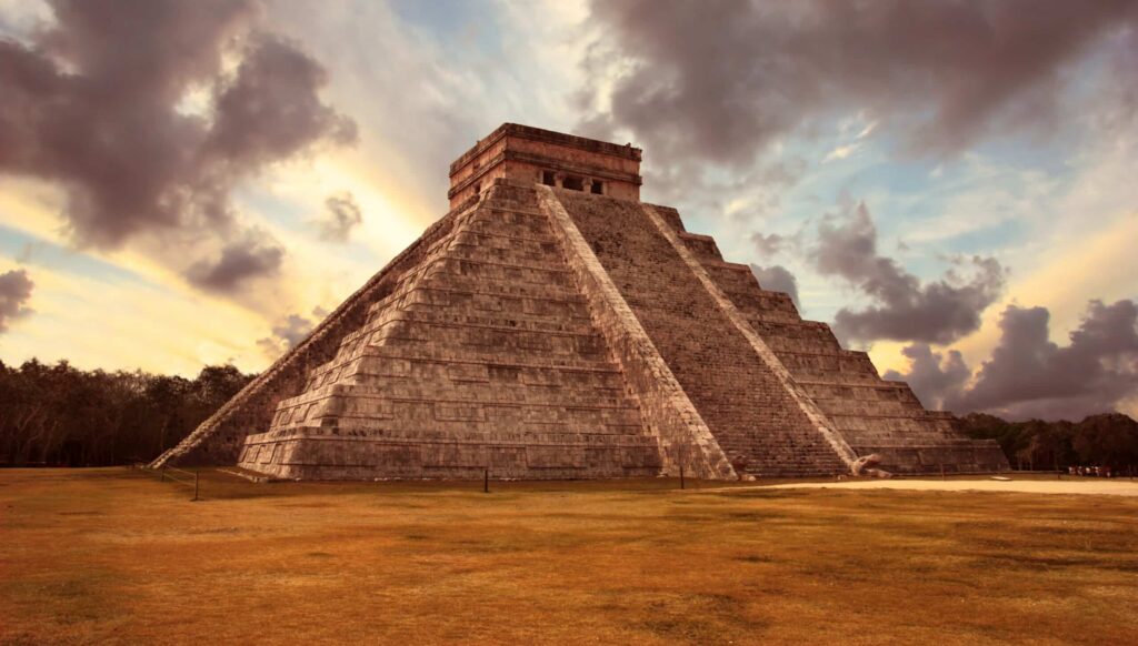 Pyramide de Chichen Itza sous un ciel nuageux au coucher du soleil, site maya emblématique au Mexique.