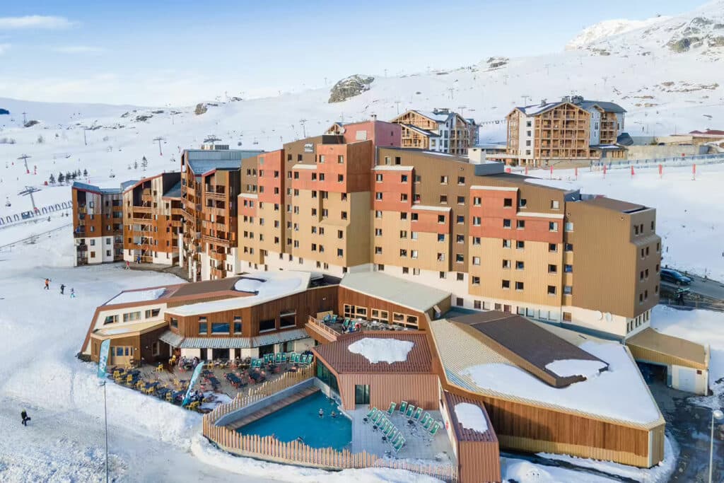 Vue aérienne d’un hôtel à la montagne avec piscine chauffée en plein hiver