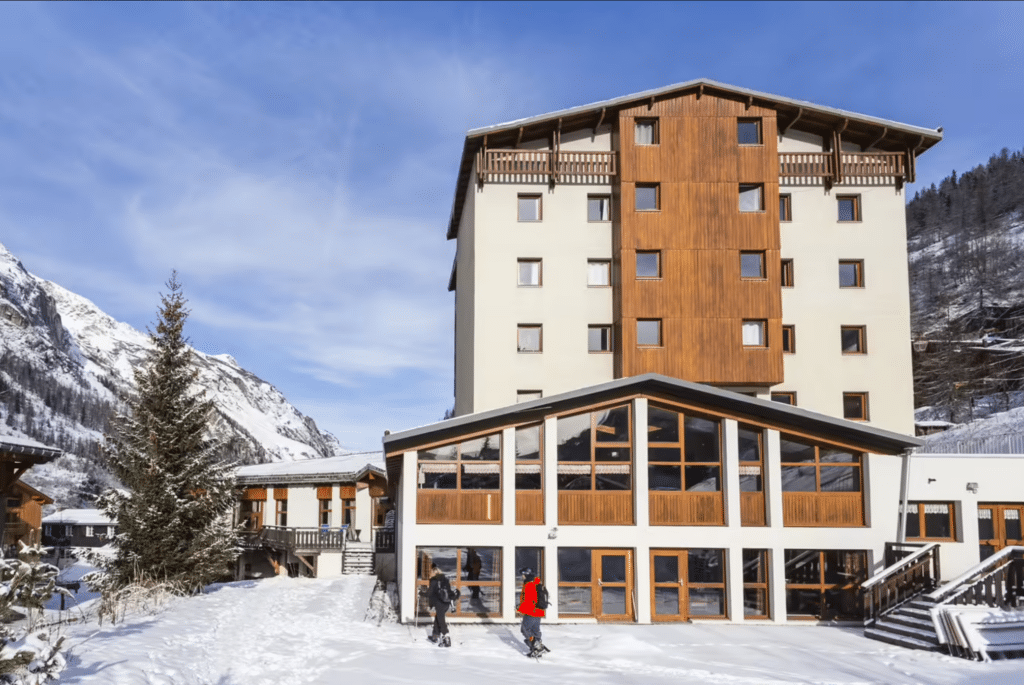 Façade d’un hôtel de montagne en hiver avec architecture boisée et neige au sol