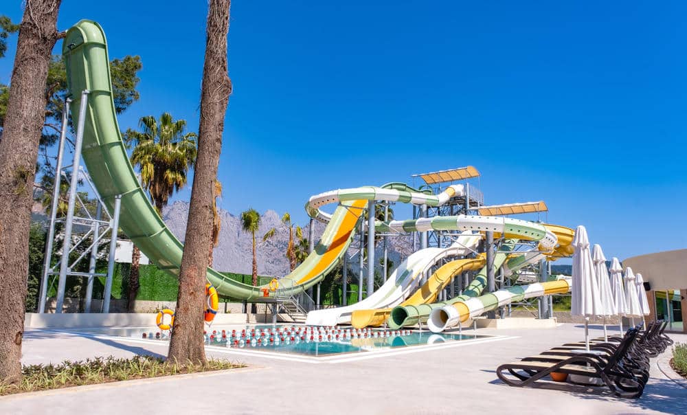 http://Grand%20parc%20aquatique%20avec%20toboggans%20colorés%20et%20piscine%20au%20pied%20d’un%20complexe%20hôtelier.