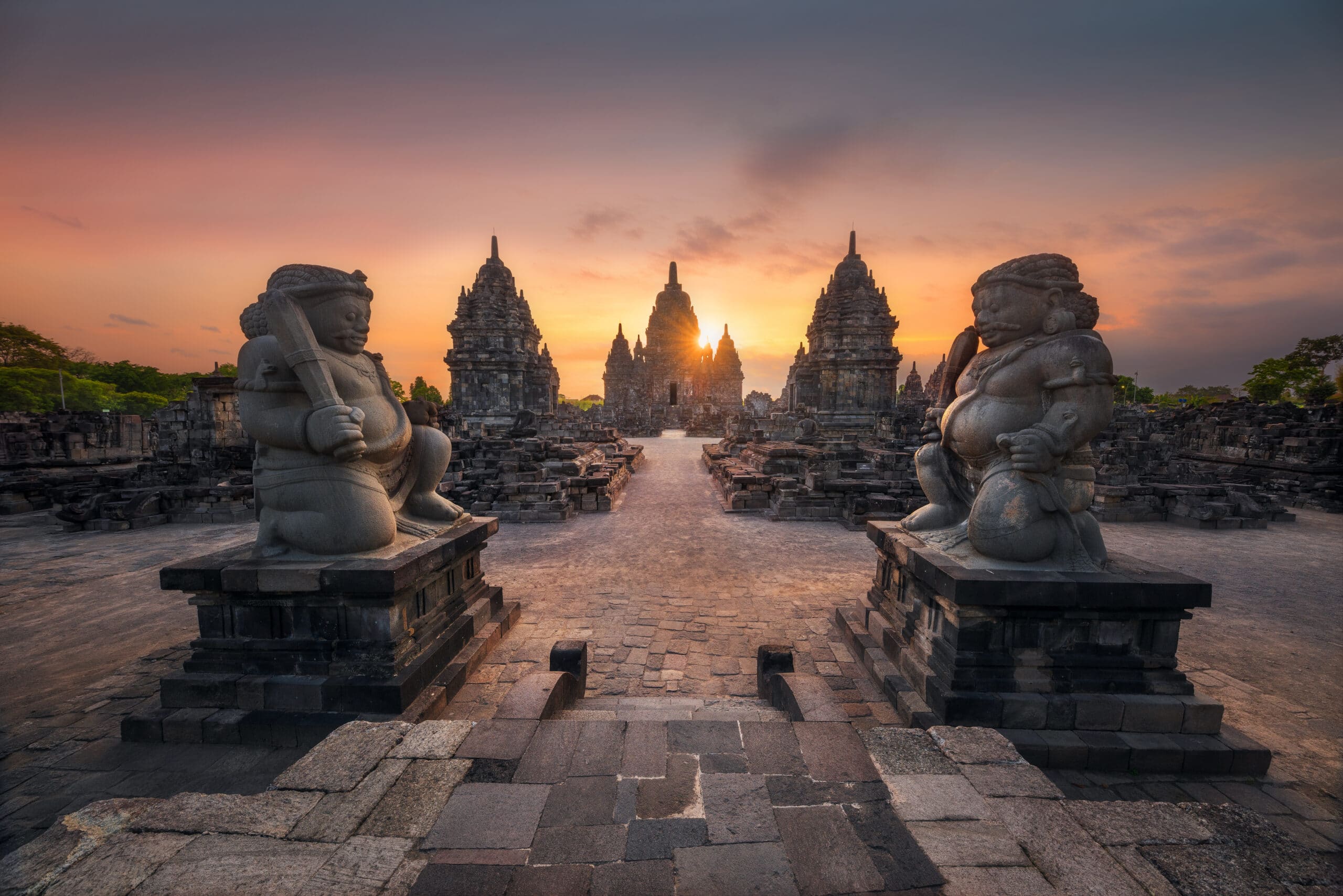 http://Temple%20hindouiste%20de%20Prambanan%20à%20Java%20au%20coucher%20du%20soleil,%20avec%20statues%20monumentales%20et%20ciel%20orangé.