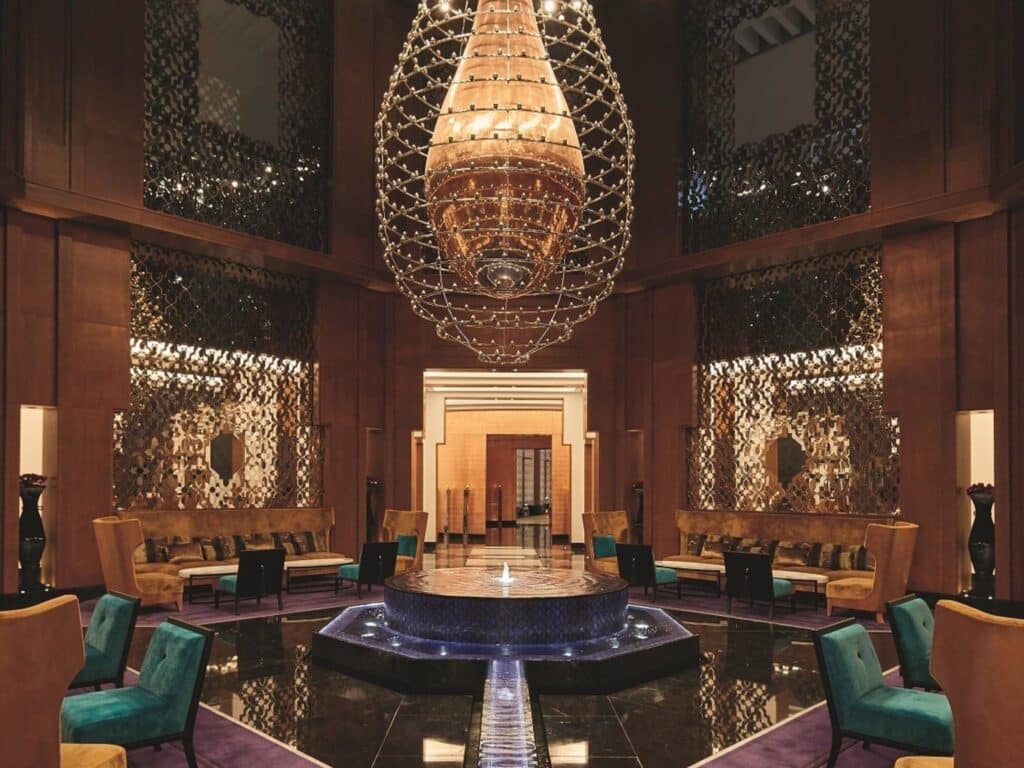 Lobby grandiose d’un palace marocain avec lustre géant et fontaine centrale