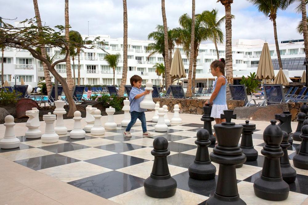 http://Deux%20enfants%20jouant%20sur%20un%20échiquier%20géant%20en%20plein%20air%20dans%20un%20hôtel.