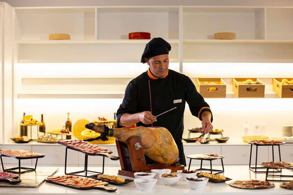 http://Chef%20en%20cuisine%20découpant%20un%20jambon%20cru%20lors%20d’un%20buffet%20gastronomique%20dans%20un%20hôtel.