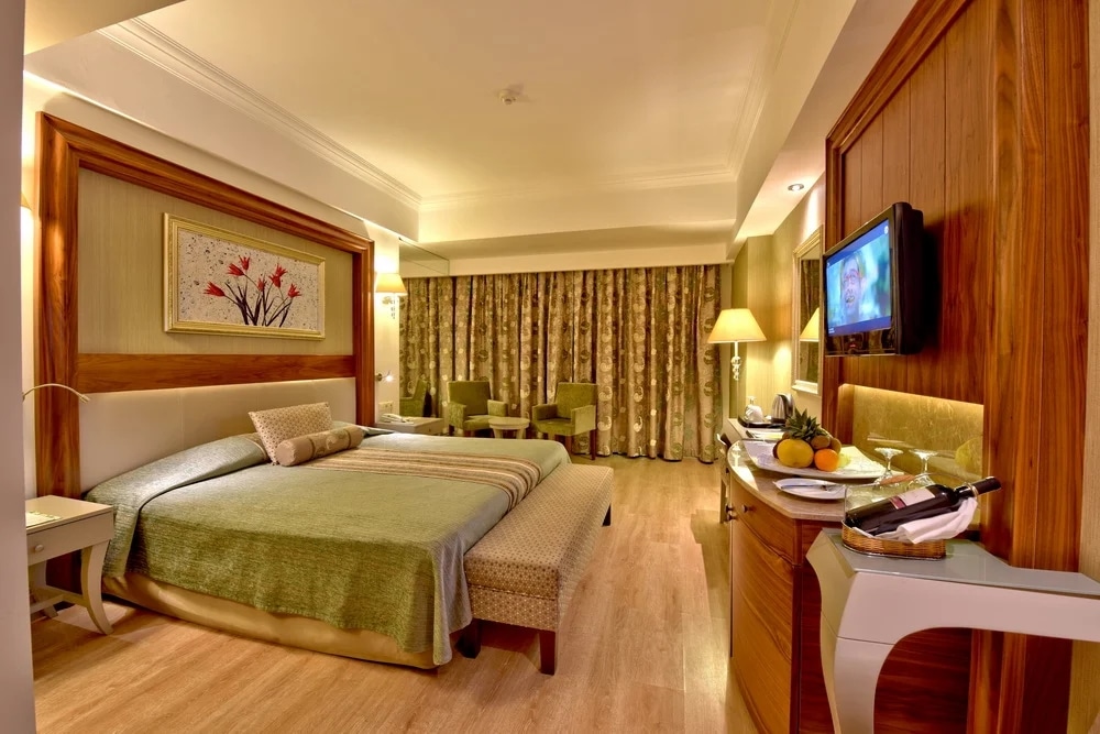 http://Chambre%20d’hôtel%20avec%20lit%20double,%20coin%20salon%20et%20mobilier%20en%20bois