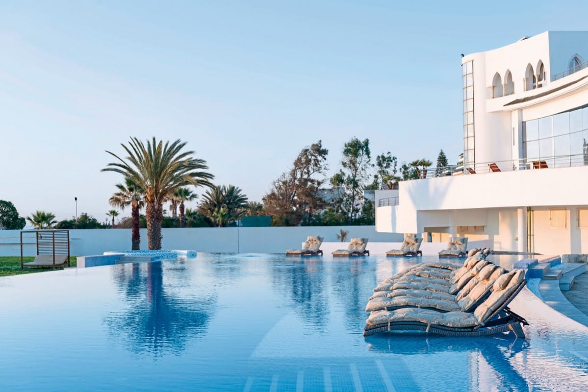 http://Piscine%20à%20débordement%20avec%20transats%20confortables%20dans%20un%20hôtel%20de%20luxe%20tunisien%20au%20coucher%20du%20soleil.