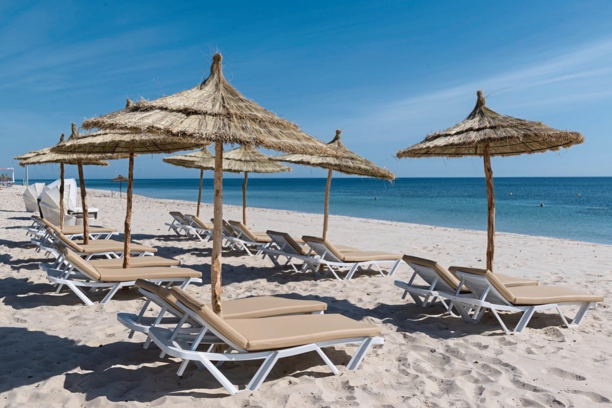 http://Plage%20de%20sable%20fin%20avec%20transats%20et%20parasols%20en%20paille%20traditionnelle%20face%20à%20la%20mer%20Méditerranée.