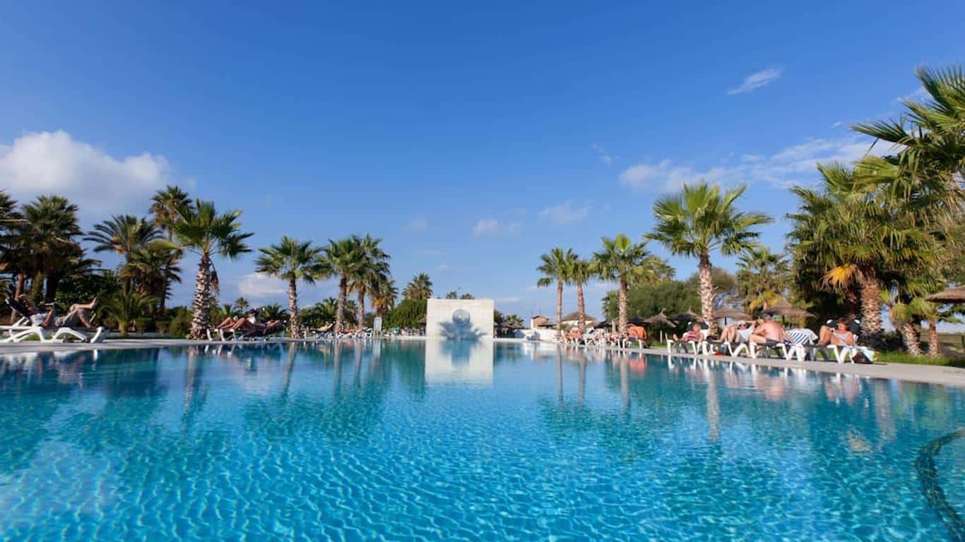 http://Piscine%20extérieure%20bordée%20de%20palmiers%20avec%20transats%20et%20ciel%20bleu.
