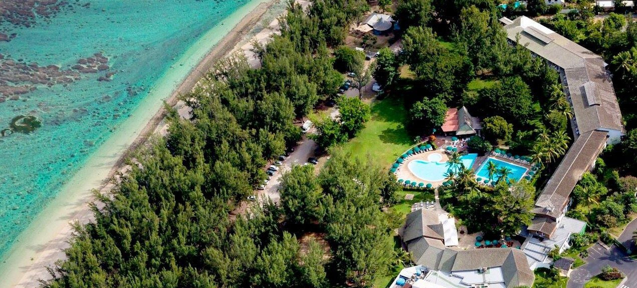 http://Vue%20aérienne%20d’un%20hôtel%20entouré%20de%20filaos%20avec%20piscine%20et%20plage%20turquoise