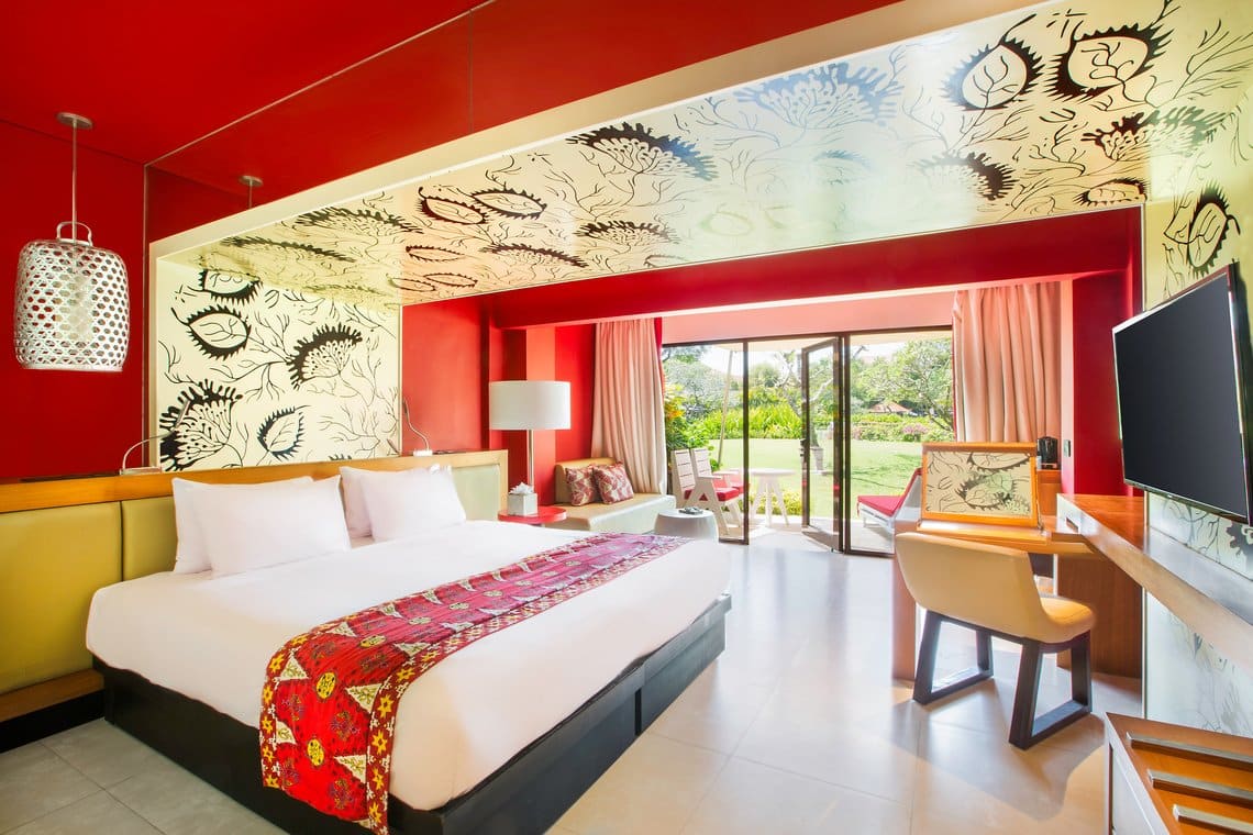 http://Chambre%20d'hôtel%20au%20design%20unique%20avec%20décoration%20rouge%20et%20vue%20sur%20un%20jardin%20tropical.