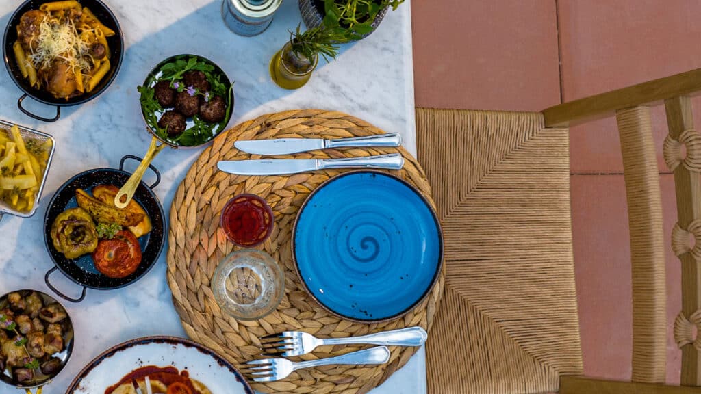 Table en terrasse avec assiette bleue, plats grecs traditionnels et spécialités méditerranéennes au Grecotel.
