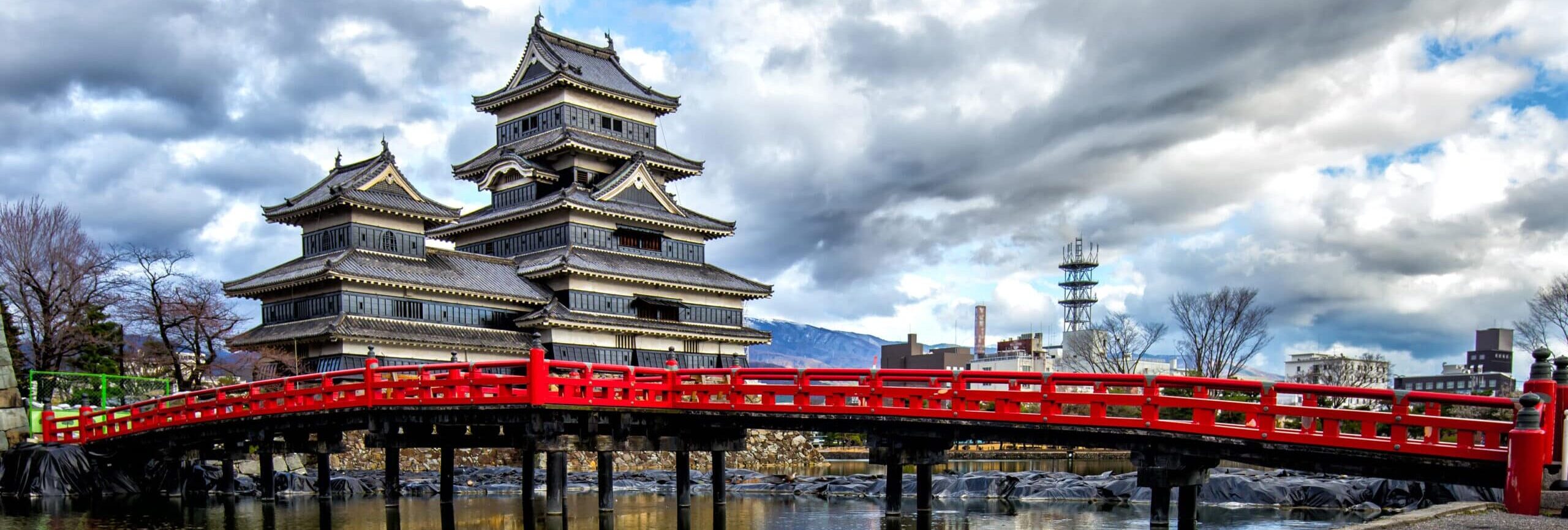 http://Le%20château%20de%20Matsumoto,%20surnommé%20le%20«%20château%20corbeau%20»,%20avec%20son%20pont%20rouge%20emblématique%20et%20des%20cygnes%20nageant%20sur%20l’eau.