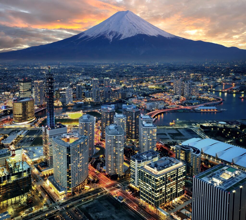 Vue panoramique de Tokyo illuminée au crépuscule avec le mont Fuji en arrière-plan.