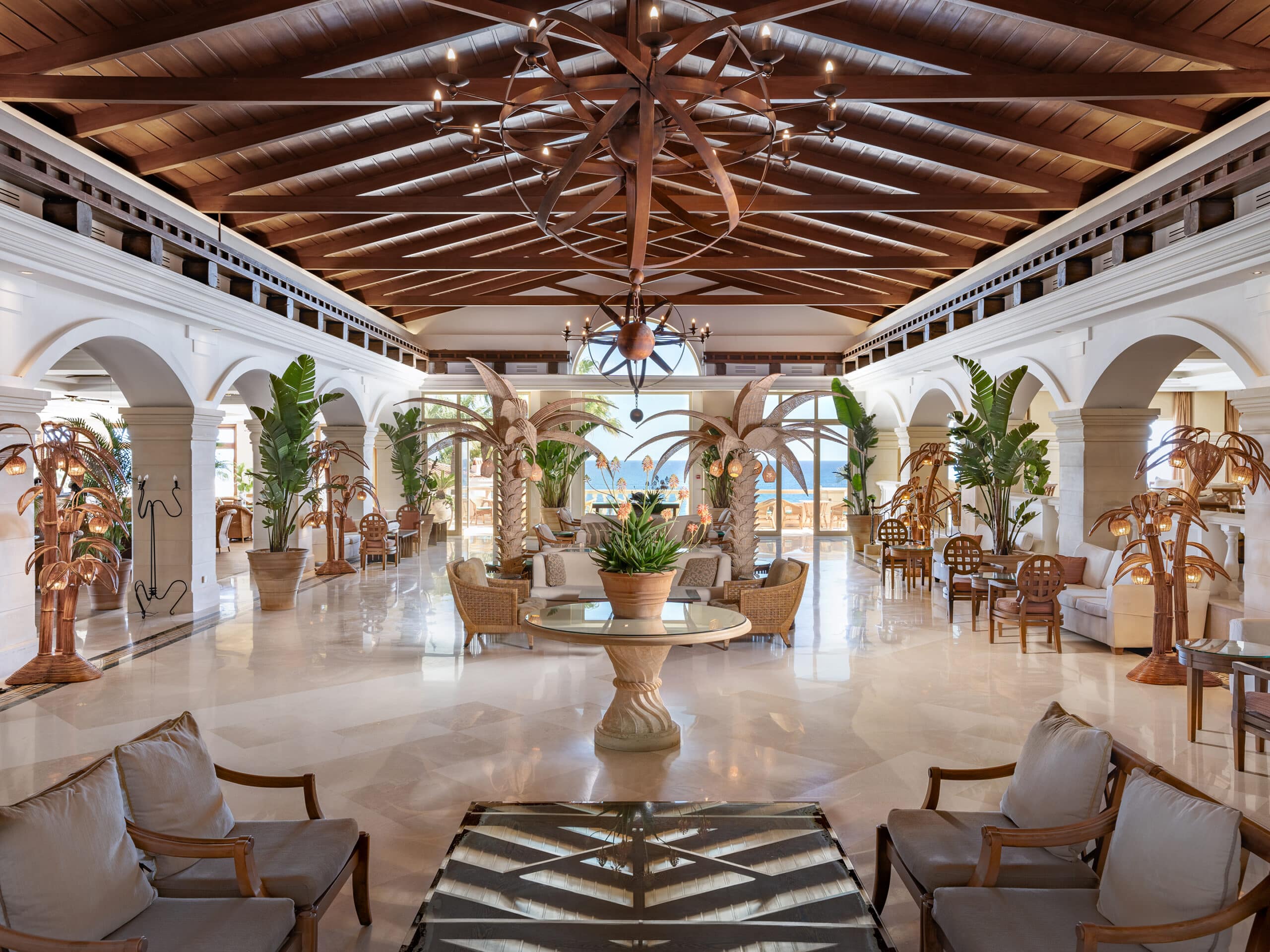 http://Hall%20spacieux%20d’un%20hôtel%20de%20luxe%20avec%20arches%20en%20pierre,%20plantes%20tropicales%20et%20vue%20sur%20la%20mer