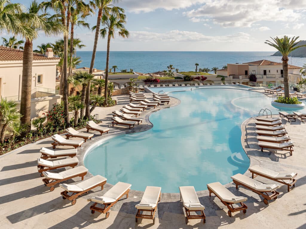 Piscine extérieure entourée de transats avec vue sur la mer Méditerranée