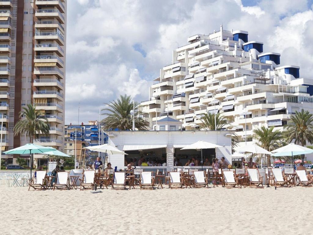 Hôtel moderne en bord de mer avec bar de plage et rangée de transats sous parasols