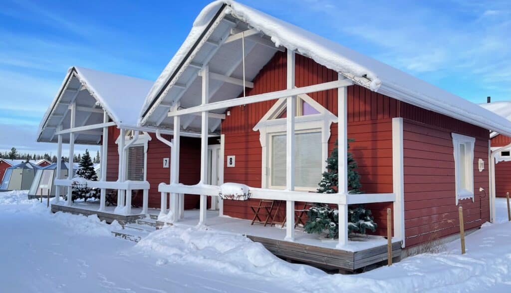 Chalets en bois rouge avec toiture enneigée dans un paysage hivernal scandinave