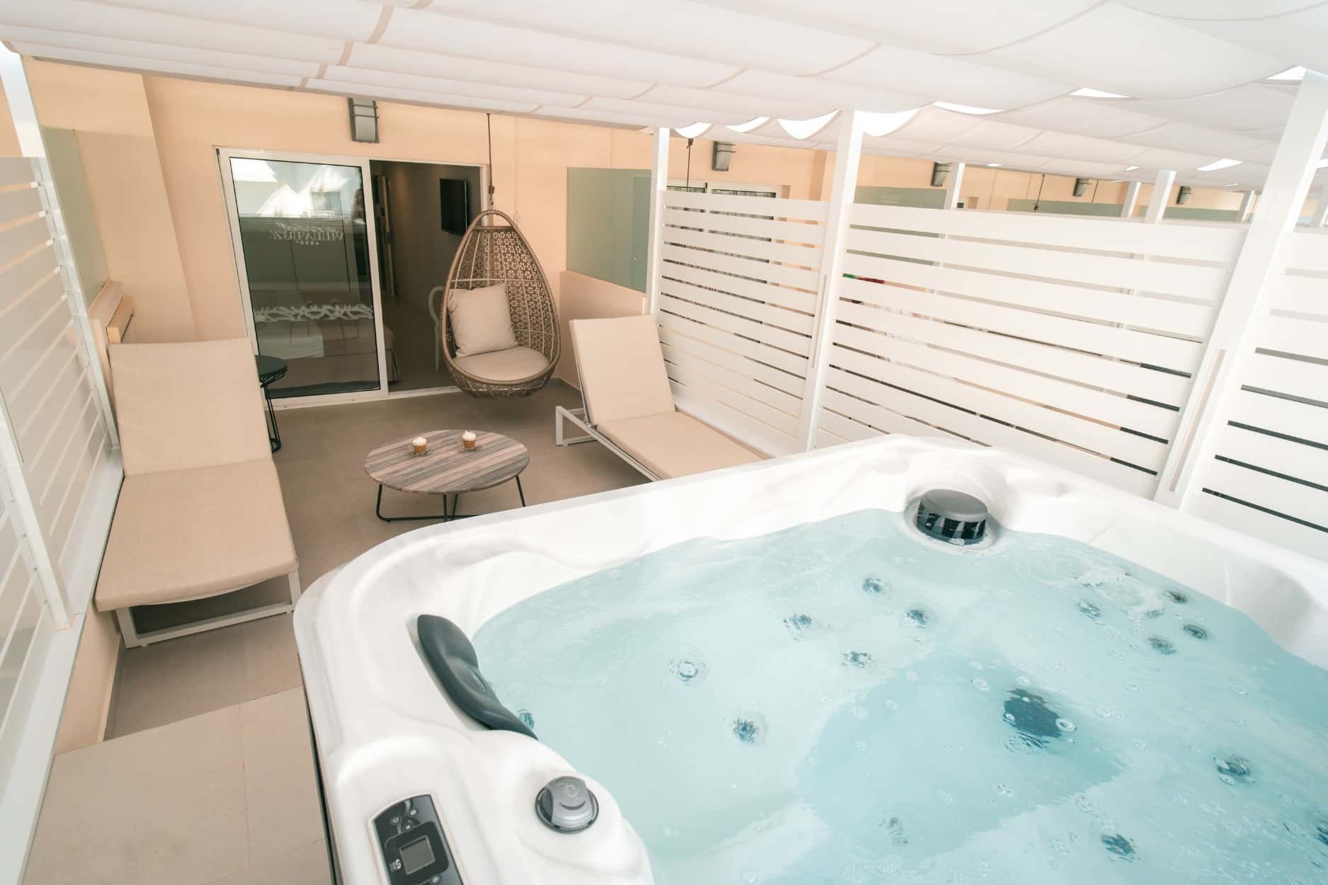 http://Terrasse%20privée%20d’une%20suite%20d’hôtel%20avec%20jacuzzi,%20transats%20et%20fauteuil%20suspendu