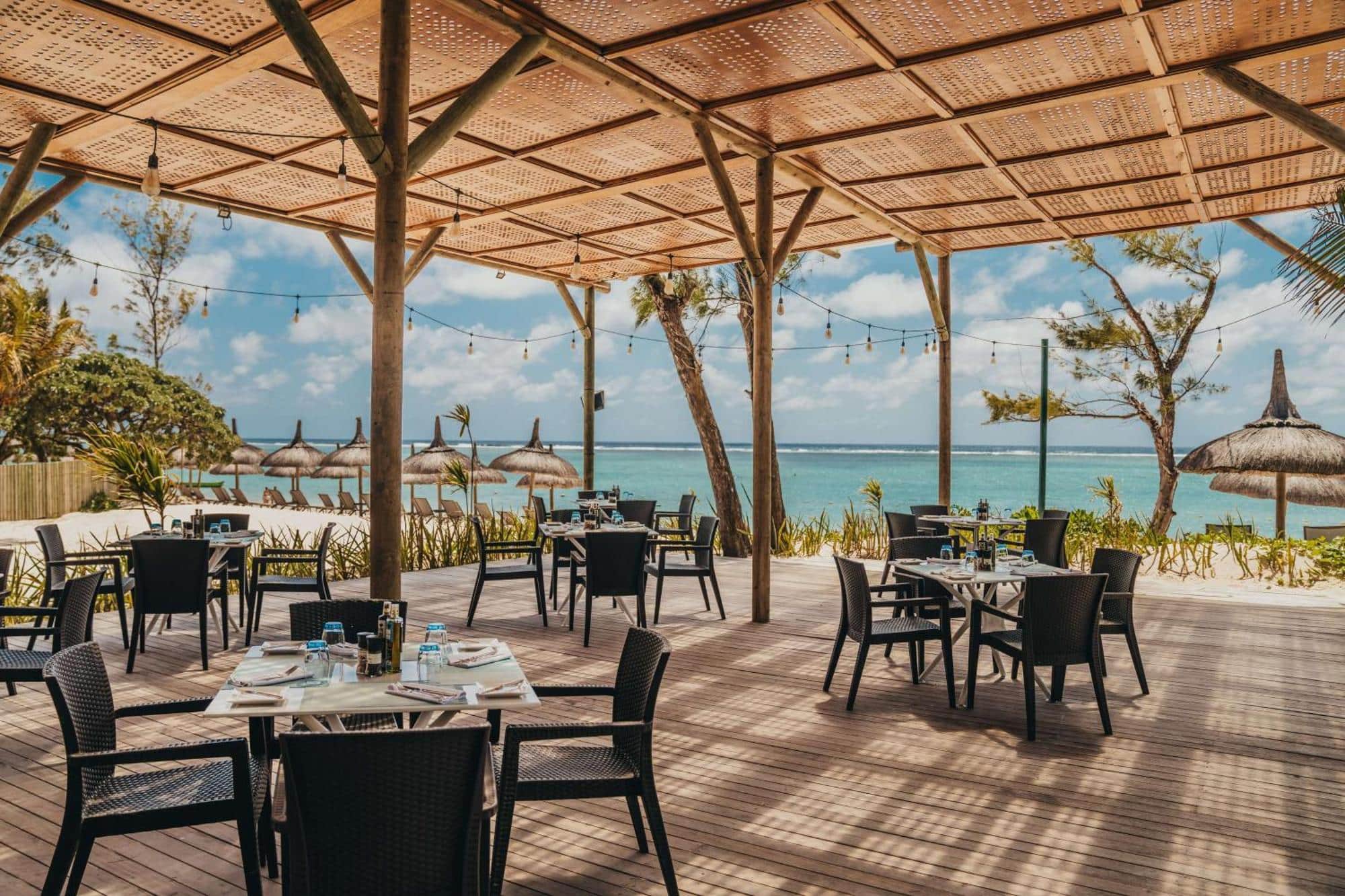 http://Terrasse%20de%20restaurant%20avec%20parasols%20en%20chaume%20face%20à%20la%20mer