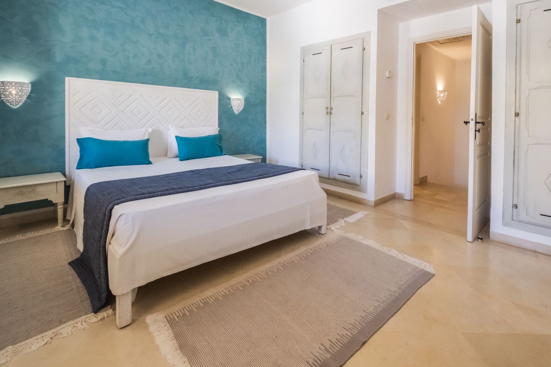 http://Chambre%20d’hôtel%20épurée%20avec%20mur%20bleu,%20mobilier%20blanc%20et%20décoration%20tunisienne
