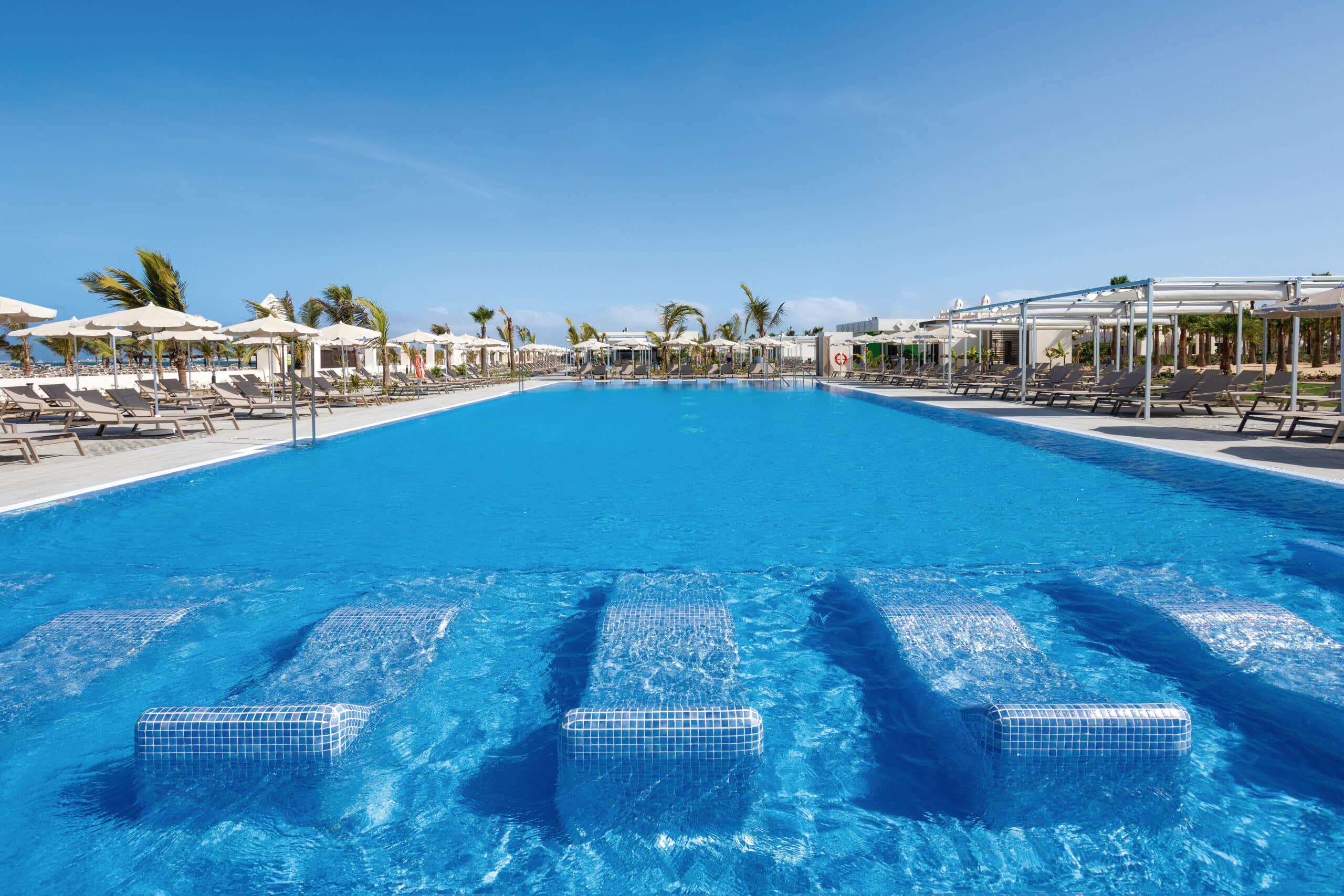 http://Grande%20piscine%20extérieure%20entourée%20de%20transats%20et%20de%20parasols%20dans%20un%20complexe%20balnéaire