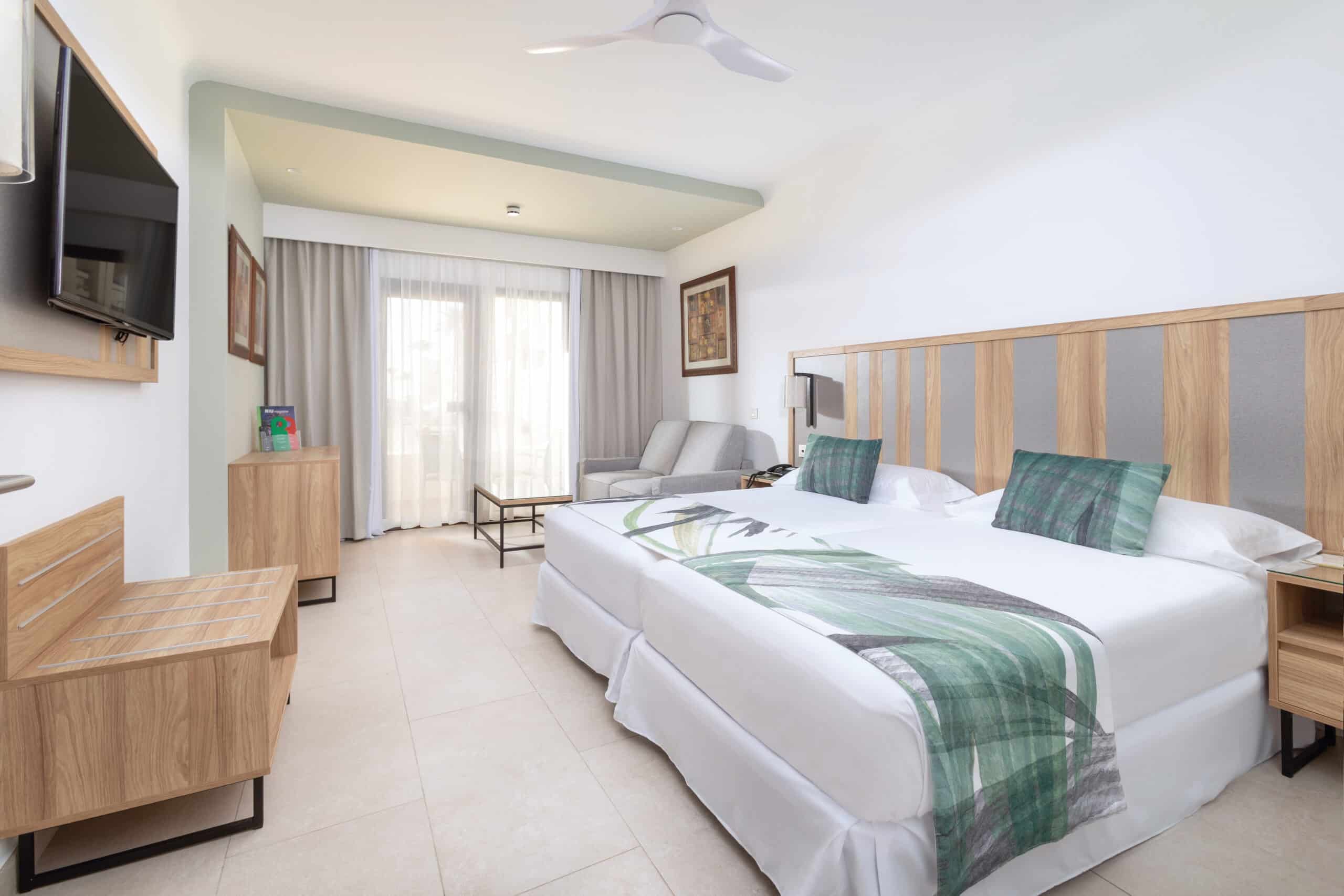 http://Chambre%20d’hôtel%20moderne%20avec%20lit%20double,%20mobilier%20en%20bois%20clair%20et%20balcon