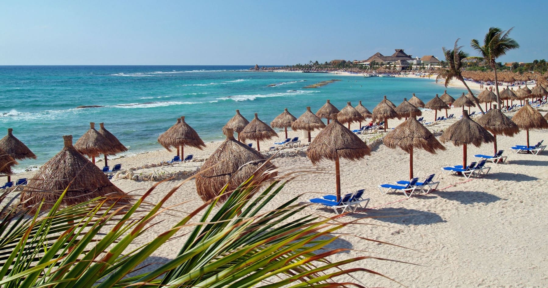 http://Plage%20de%20sable%20blanc%20avec%20transats%20et%20palapas%20face%20à%20une%20mer%20turquoise.