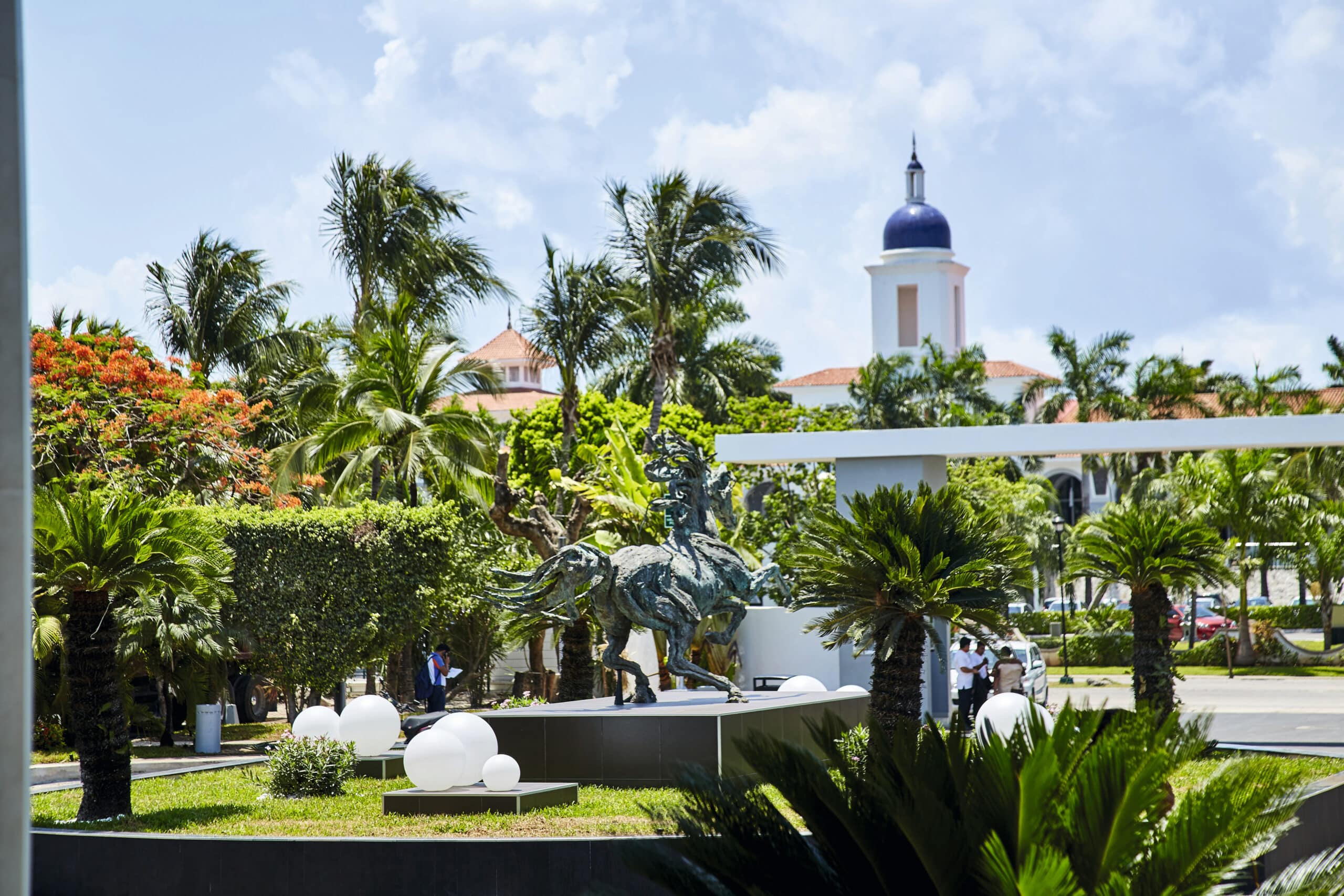 http://Jardin%20d’hôtel%20avec%20sculpture%20de%20cheval%20et%20végétation%20tropicale%20à%20l’entrée%20d’un%20resort