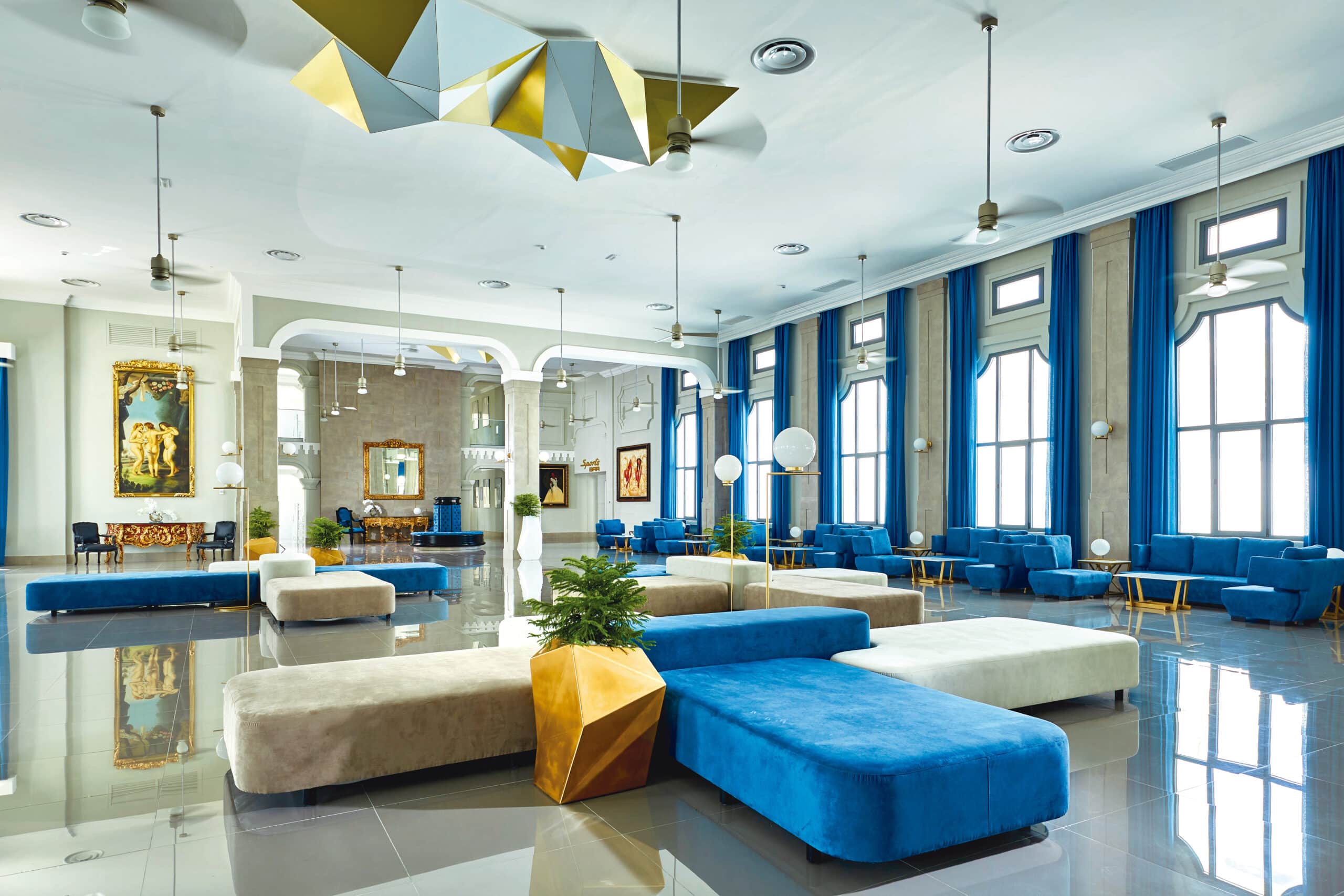 http://Hall%20d’accueil%20spacieux%20avec%20mobilier%20bleu,%20grandes%20baies%20vitrées%20et%20éléments%20artistiques.