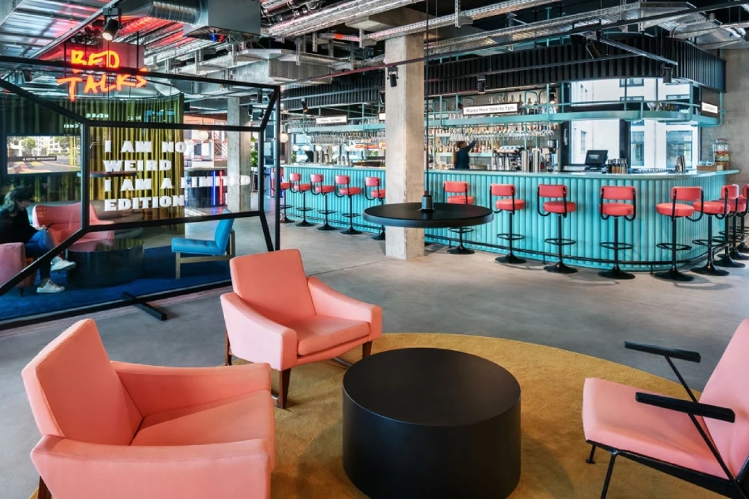 http://Lobby%20contemporain%20d’hôtel%20avec%20fauteuils%20roses,%20bar%20turquoise%20et%20ambiance%20urbaine%20tendance