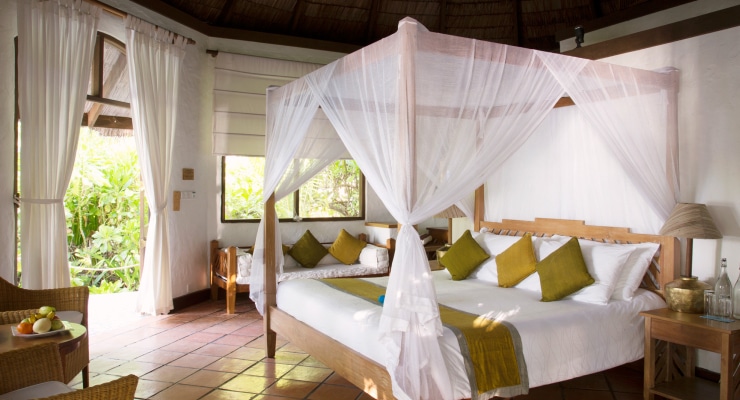 http://Chambre%20lumineuse%20avec%20lit%20à%20baldaquin,%20coussins%20verts%20et%20vue%20sur%20jardin