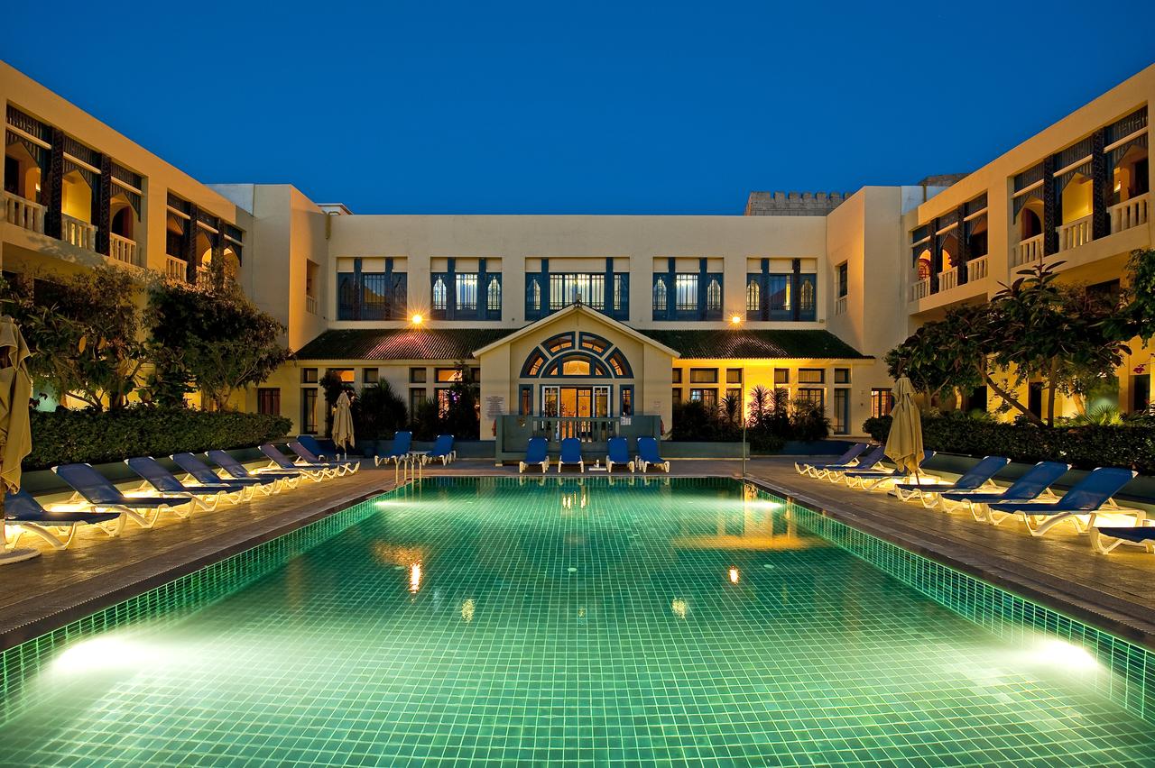 http://Piscine%20centrale%20éclairée%20dans%20une%20cour%20intérieure%20d’hôtel%20tunisien%20en%20soirée