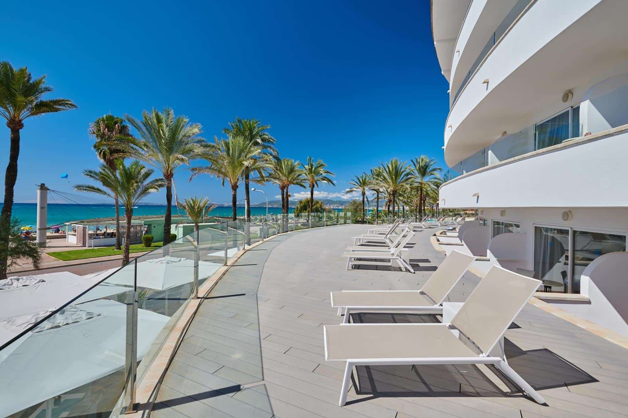 http://Terrasse%20d’hôtel%20moderne%20avec%20transats%20donnant%20sur%20la%20mer%20et%20bordée%20de%20palmiers