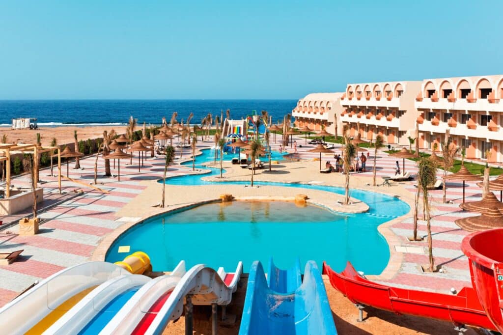 Espace aquatique d’un hôtel avec piscines, toboggans colorés et vue sur la mer.