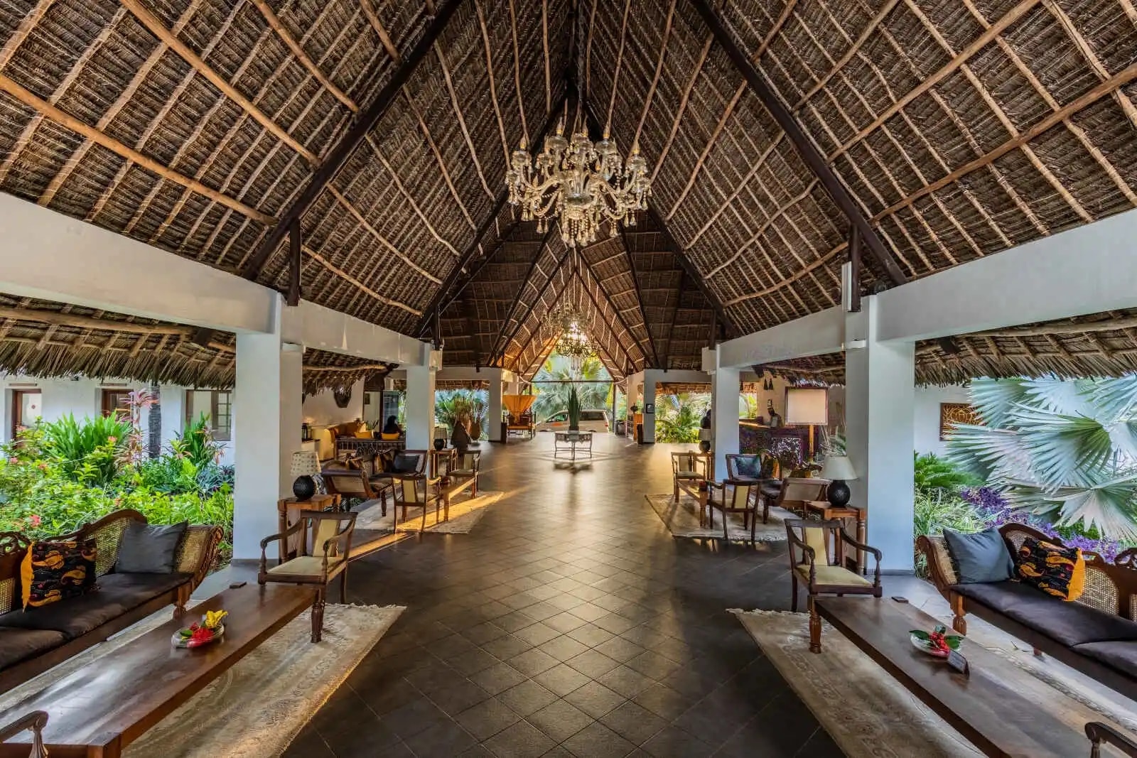 http://Lobby%20ouvert%20d’un%20hôtel%20tropical%20avec%20toit%20en%20chaume%20et%20mobilier%20en%20bois%20exotique