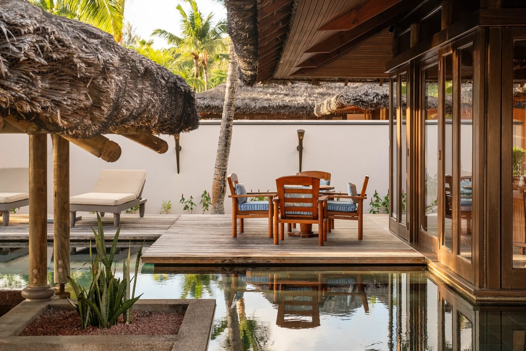http://Terrasse%20privative%20avec%20table%20en%20bois%20et%20bassin%20calme%20dans%20une%20villa%20tropicale%20des%20Seychelles.