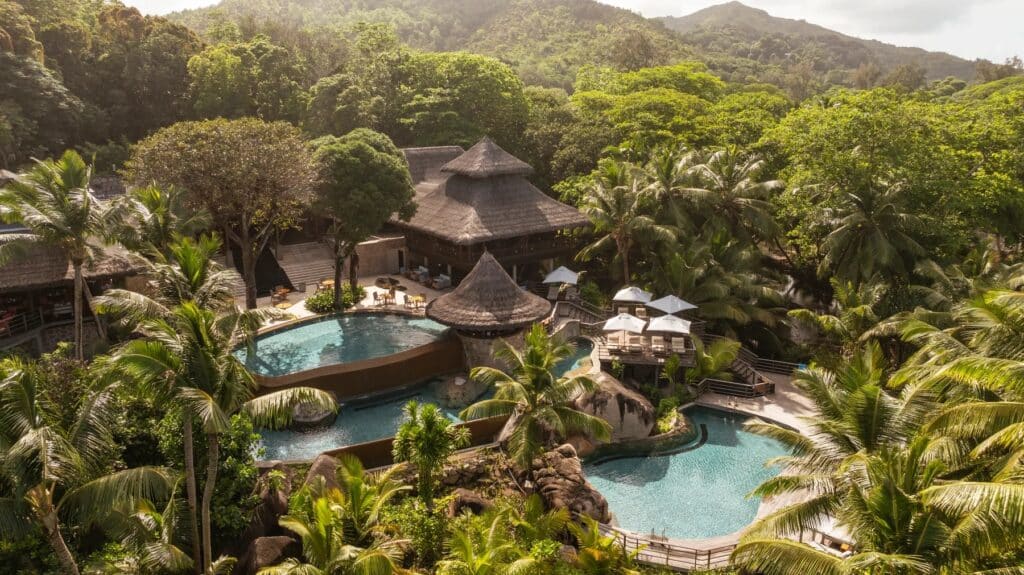 Vue aérienne d’un complexe hôtelier avec piscines en cascade au cœur de la forêt tropicale aux Seychelles.