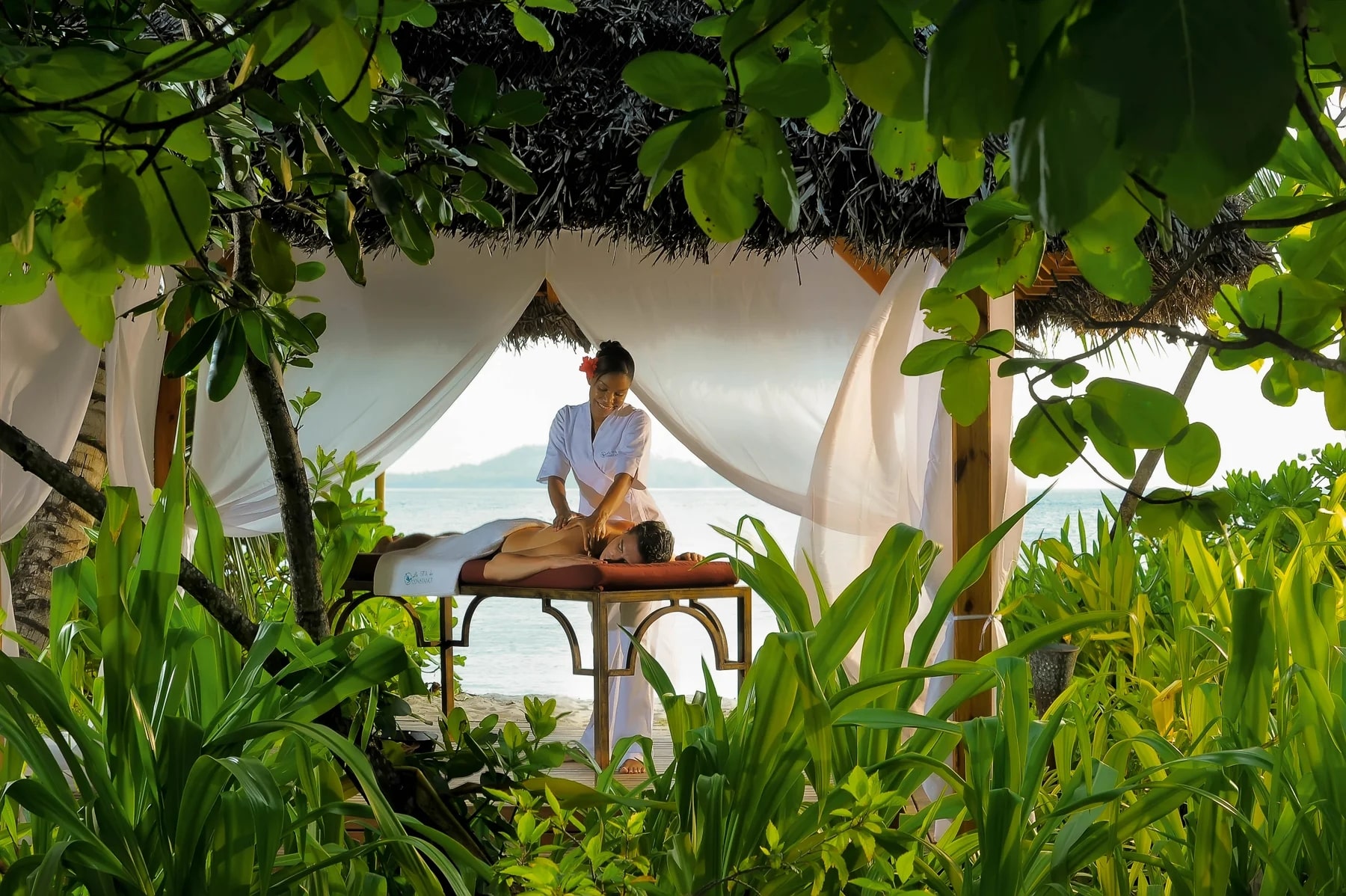 http://Massage%20relaxant%20en%20extérieur%20dans%20un%20pavillon%20spa%20en%20pleine%20nature%20tropicale%20face%20à%20la%20mer%20aux%20Seychelles