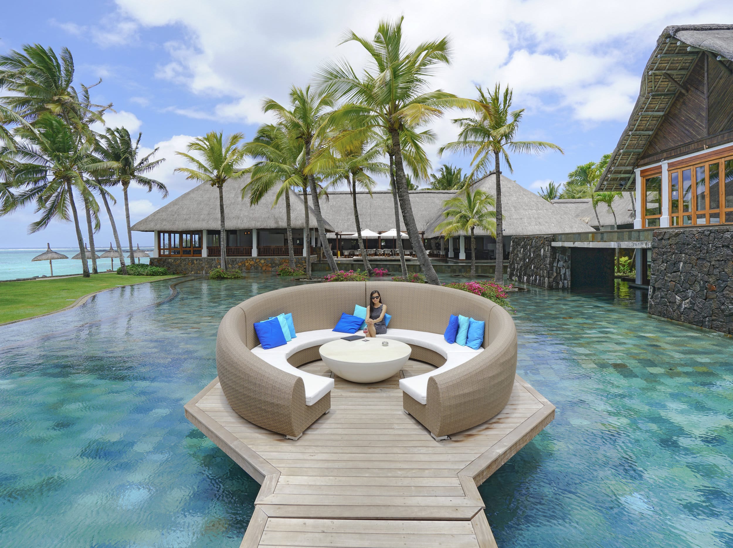 http://Espace%20lounge%20circulaire%20sur%20une%20terrasse%20en%20bois%20au-dessus%20d’une%20piscine%20dans%20un%20resort%20tropical%20de%20luxe%20à%20l’île%20Maurice.