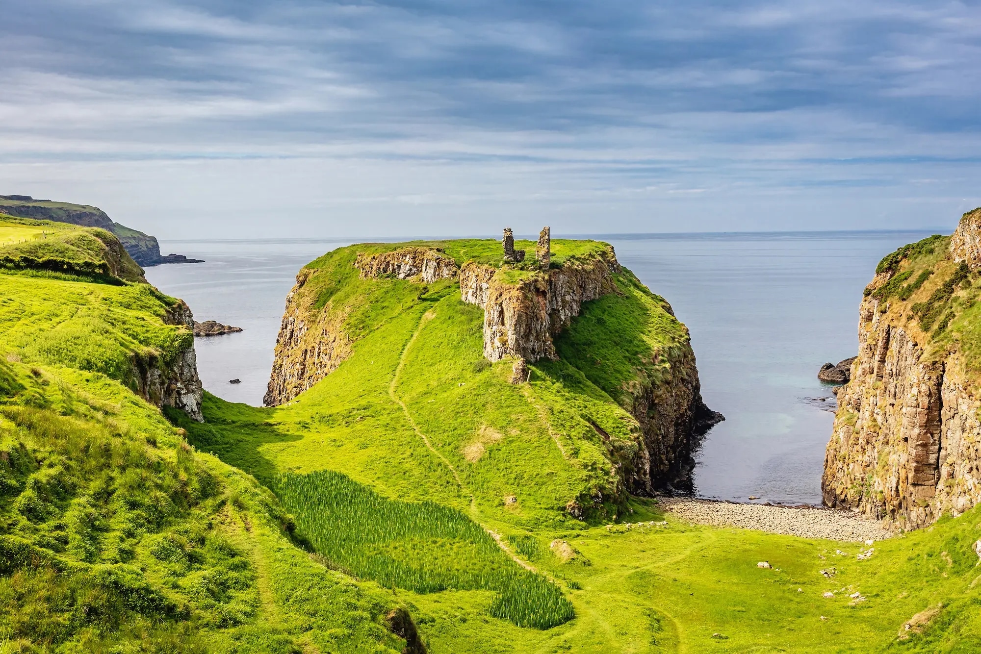 http://Paysage%20côtier%20avec%20falaises%20verdoyantes%20et%20ruines%20surplombant%20la%20mer.