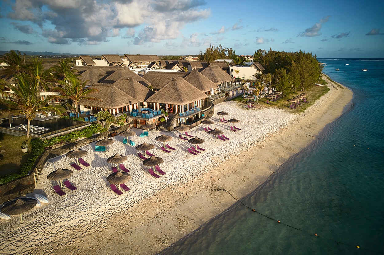 http://Hôtel%20en%20bord%20de%20plage%20à%20l’Île%20Maurice%20avec%20transats%20et%20toits%20de%20chaume