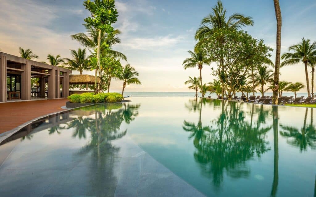 Piscine à débordement bordée de palmiers avec vue sur la mer en Thaïlande