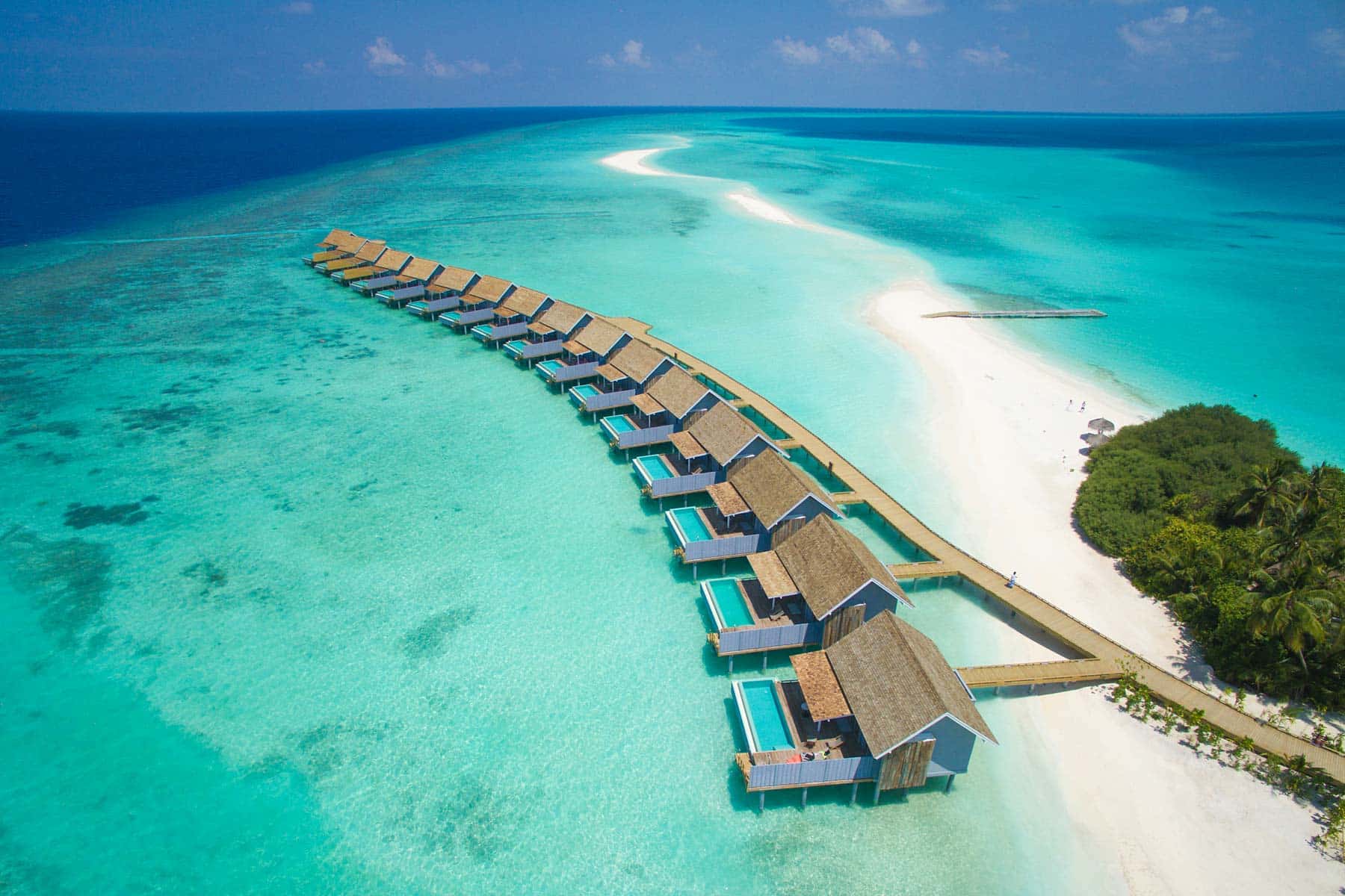 http://Vue%20aérienne%20de%20villas%20de%20luxe%20sur%20pilotis%20alignées%20au-dessus%20d’un%20lagon%20turquoise%20aux%20Maldives