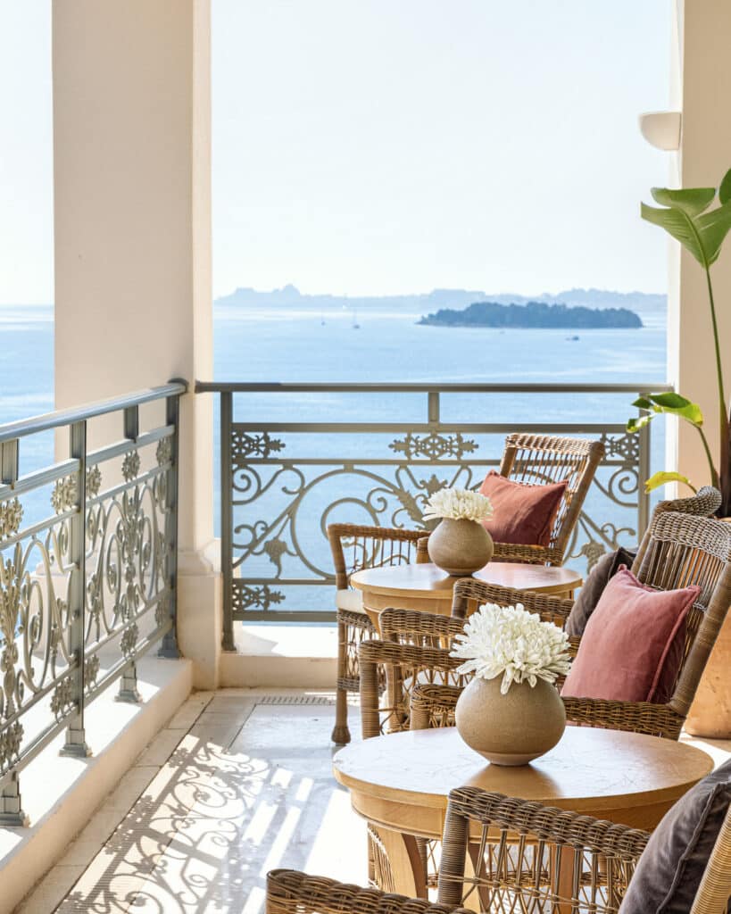 Fauteuils et tables en rotin sur une terrasse donnant sur l’océan