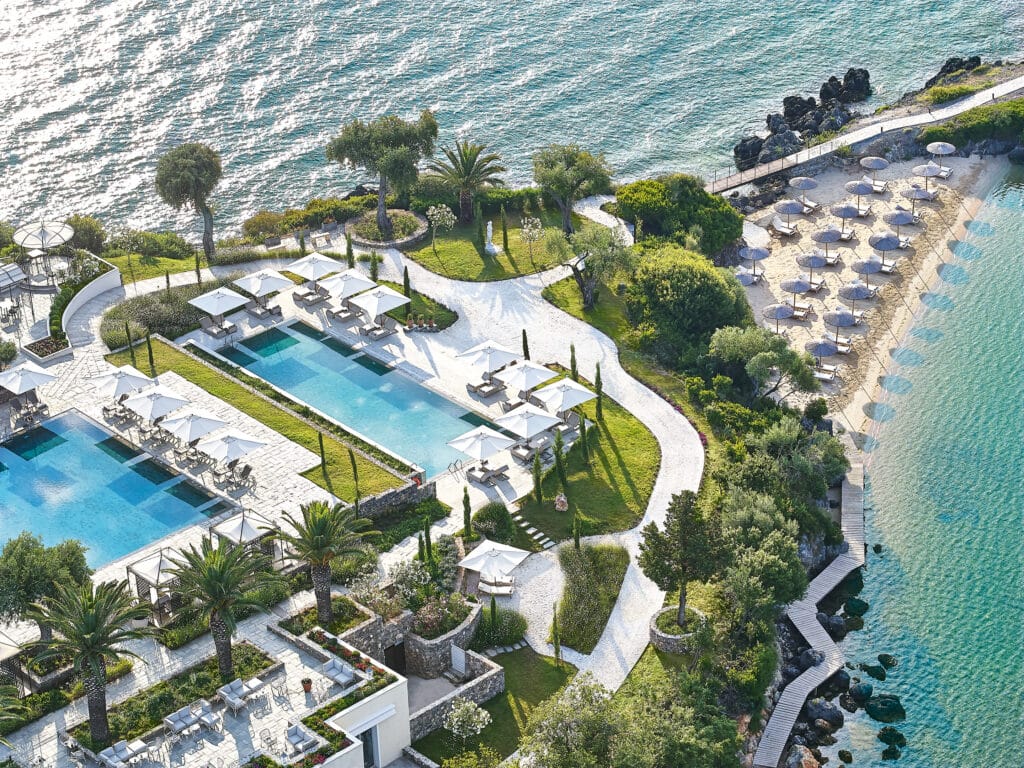 Vue aérienne d’un complexe hôtelier de luxe avec piscines, plage privée et mer turquoise.