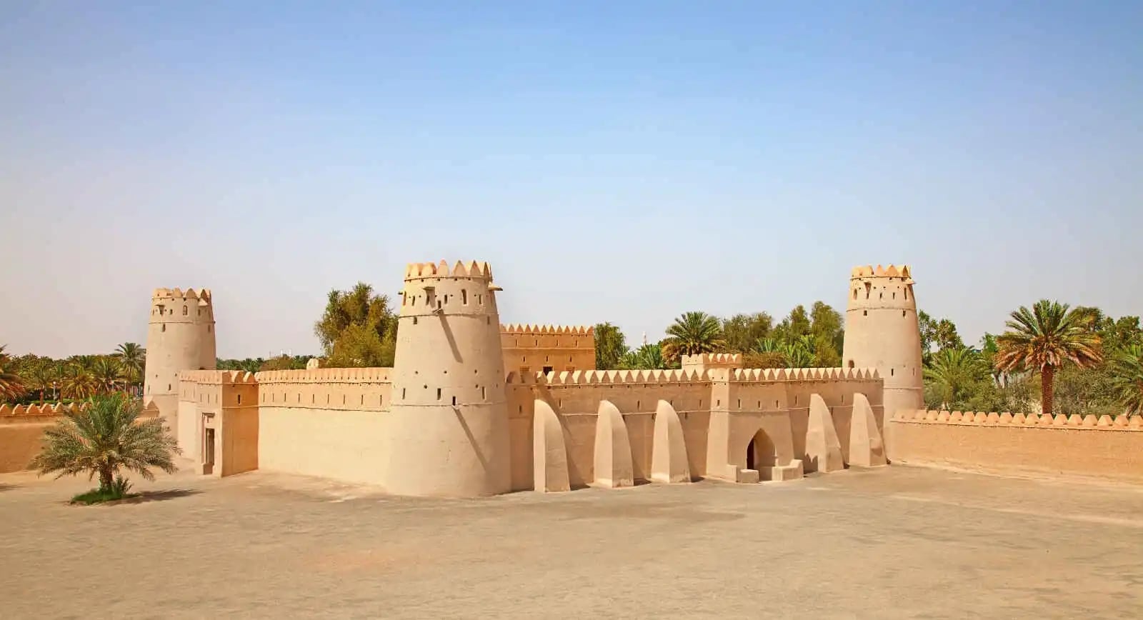http://Le%20fort%20historique%20d'Al%20Jahili%20en%20pisé%20à%20Al%20Ain,%20entouré%20de%20palmiers,%20sous%20un%20ciel%20clair.