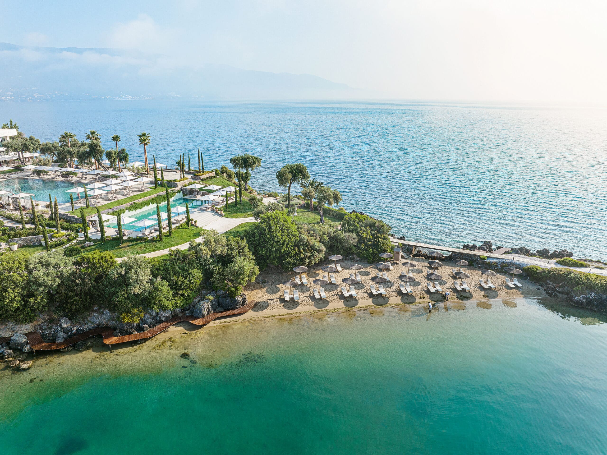http://Vue%20aérienne%20d’une%20plage%20privée%20et%20de%20piscines%20entourées%20de%20verdure%20au%20bord%20de%20la%20mer%20en%20Grèce.